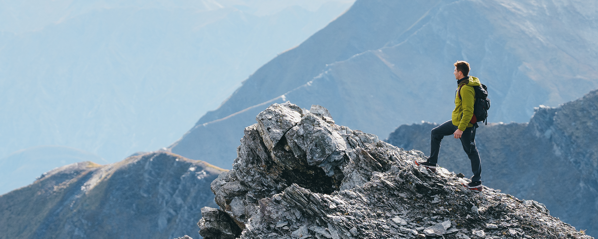 Sun shines on a woman while she smiles wearing Outdoor Research Aspire 3L Jacket in Oyster/White.