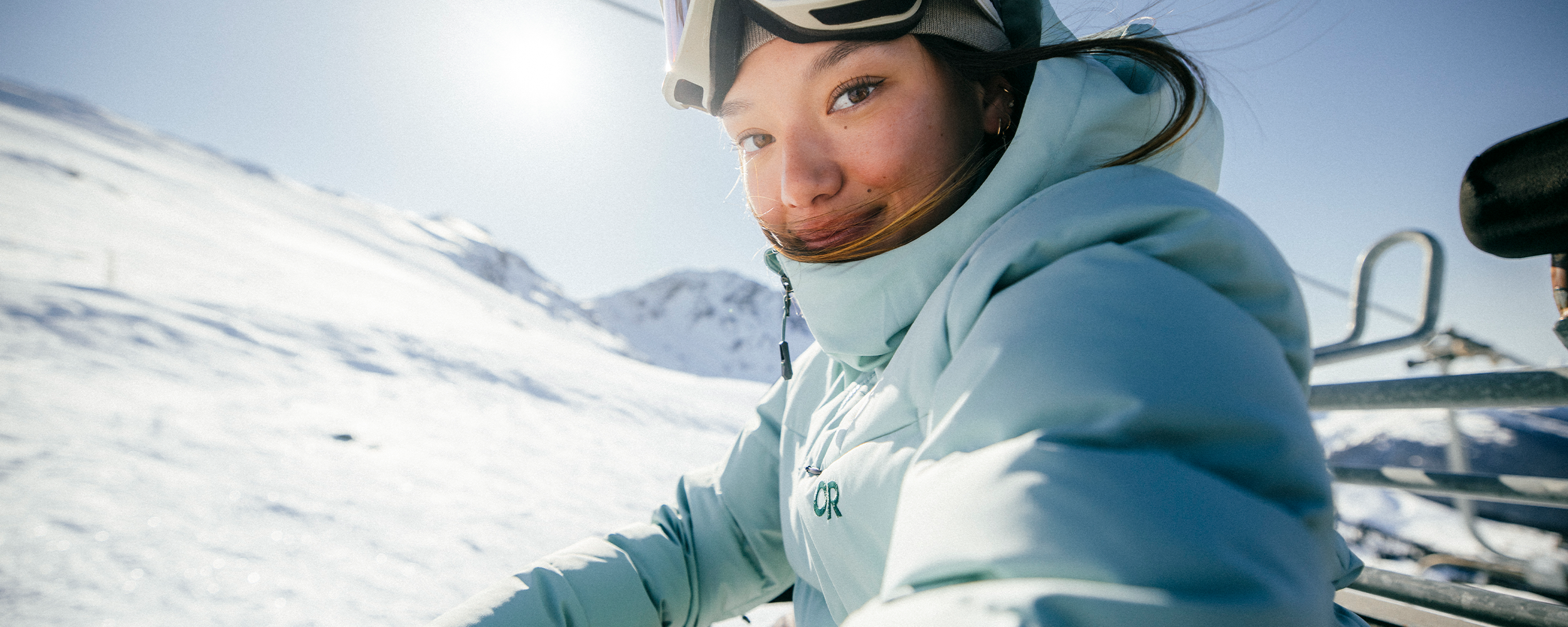 Two Females sit outside their Van in the snow to gear up in their Outdoor Research ski Outerwear. 