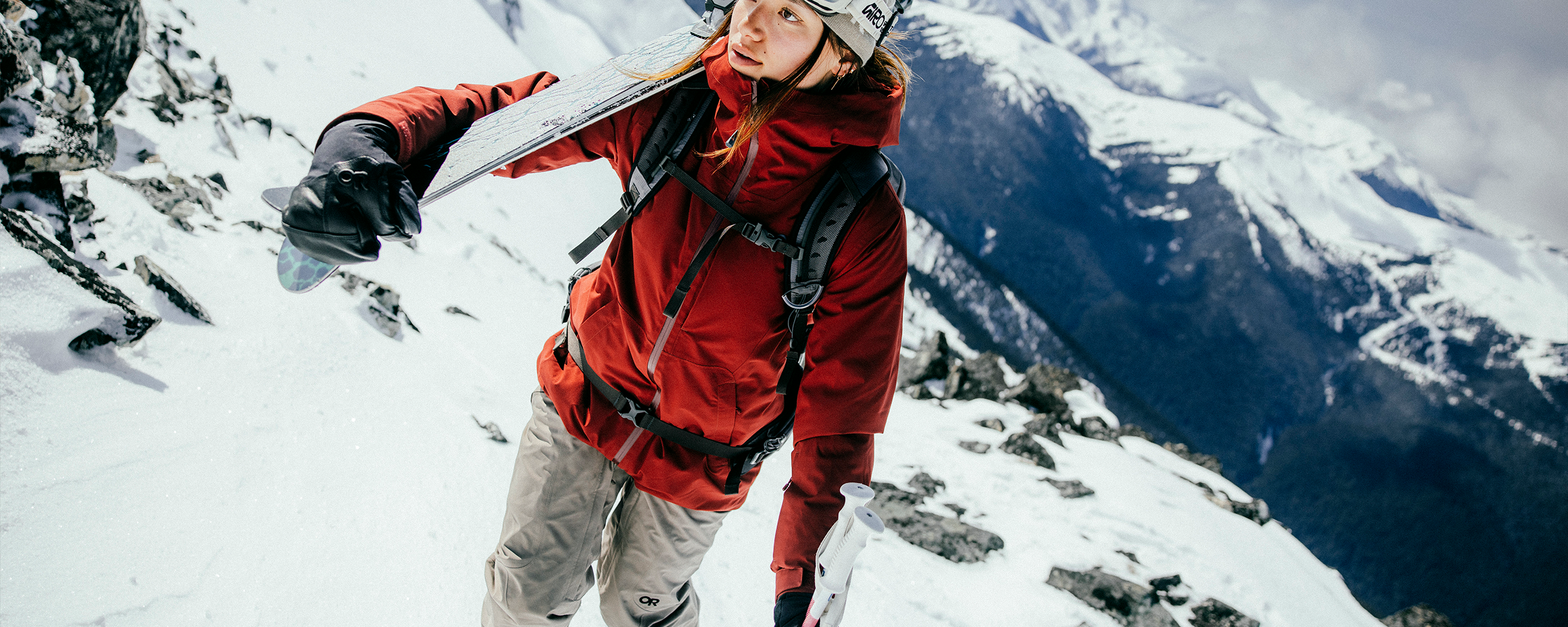 Female skiing with trees in the background wearing Outdoor Research Women's Powderverse Jacket Oyster/Sable and Women's Powderverse Pants Sable. 