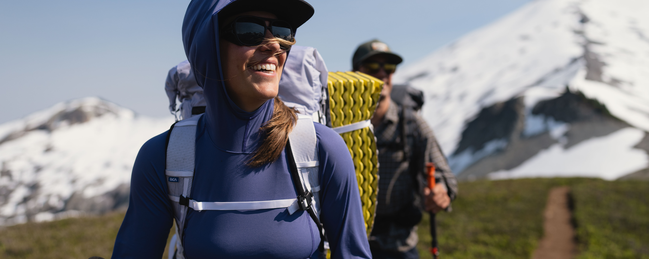 A woman smiles while putting skins on her skis while out on a ski tour.