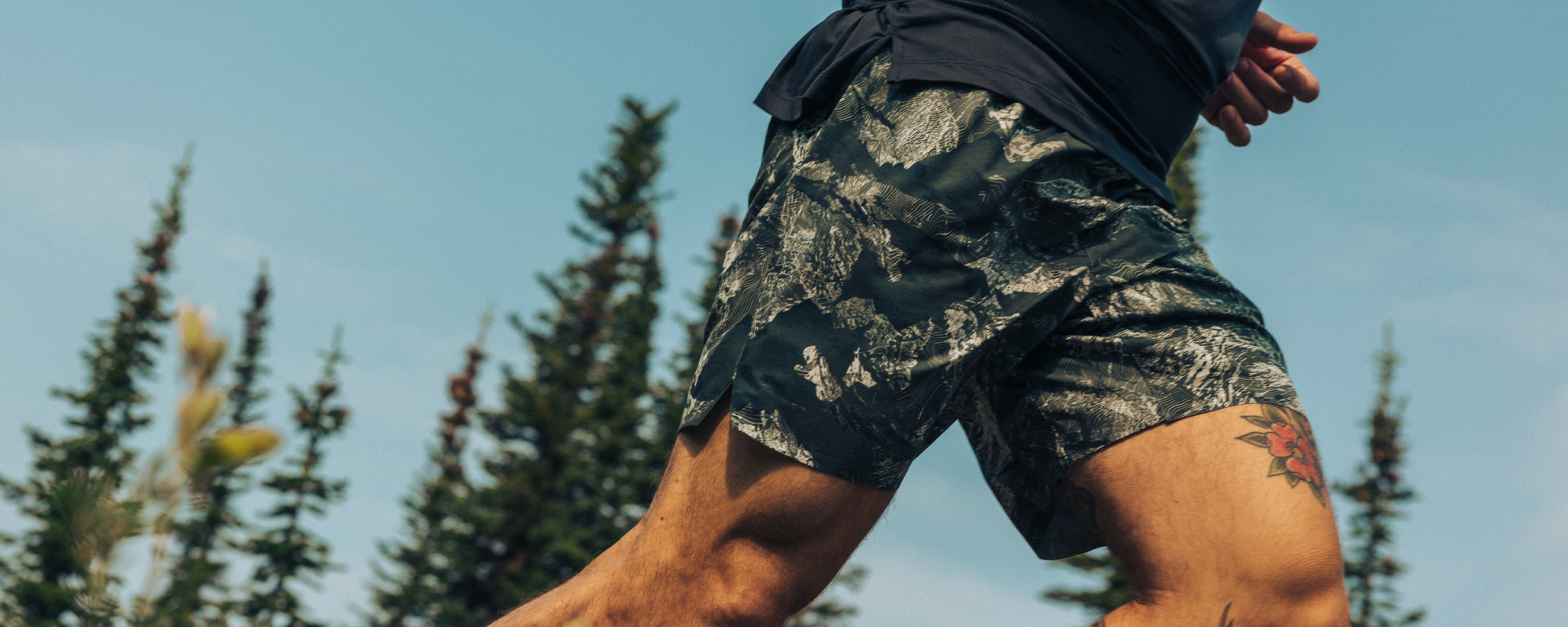 Two friends stride through a dry field under the sun wearing Outdoor Research Sportswear. 