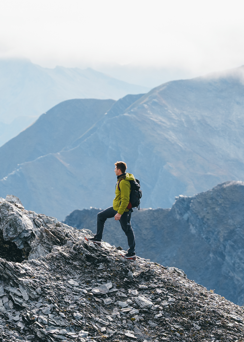 Sun shines on a woman while she smiles wearing Outdoor Research Aspire 3L Jacket in Oyster/White.
