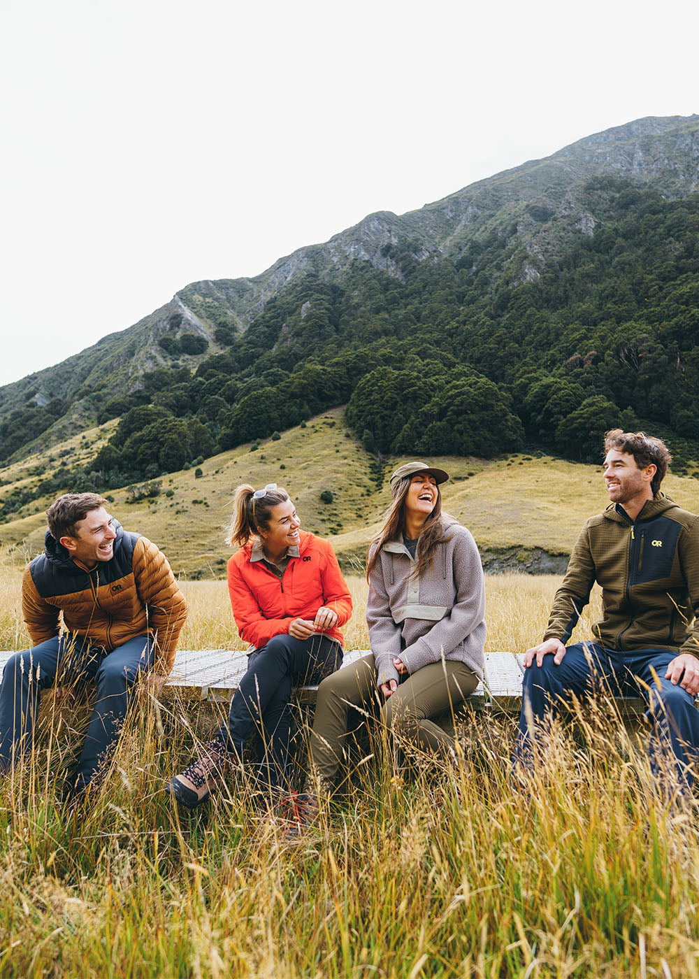 A group of friends climb to the viewpoint on a hike while wearing Outdoor Research outerwear and sportswear. 