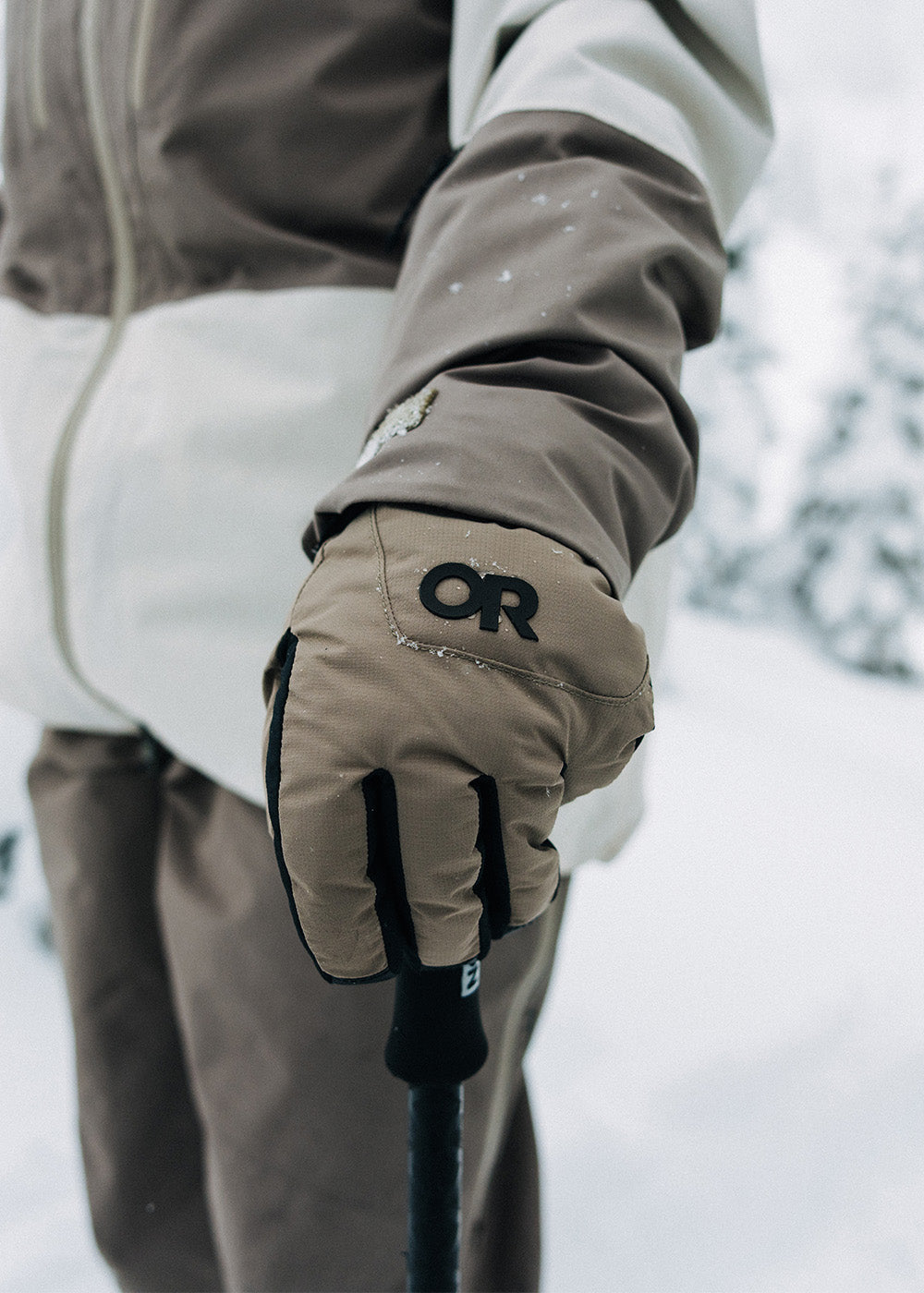 A skier holds their ski poles wearing the Outdoor Research Women's Revolution Undercuff GORE-TEX Gloves in Sable.