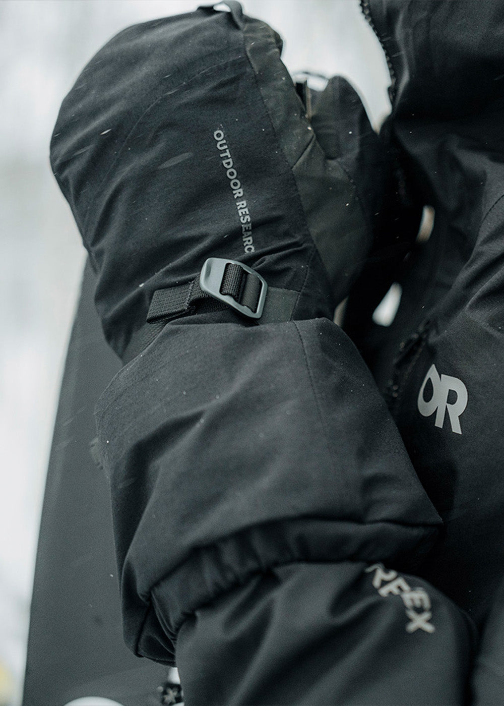 Athlete Max Djenohan climbs a mountain while gripping a Pickaxe with the Outdoor Research Team Gore-Tex 3-Finger Gloves in Black. 