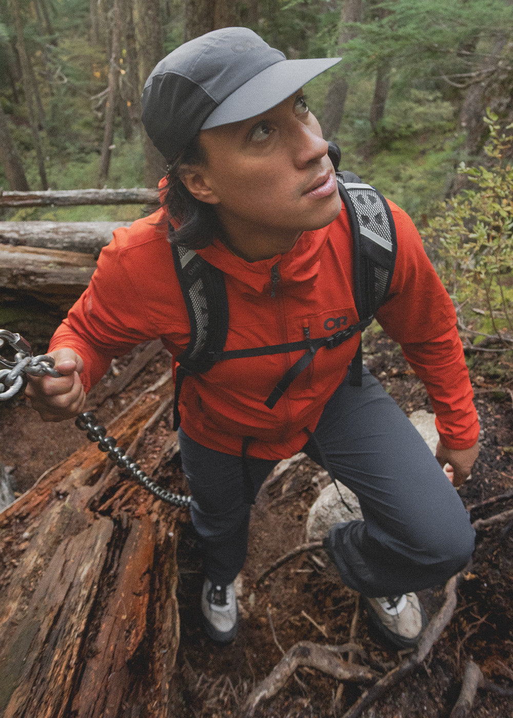 Man crouches on a branch of a tree he climbed while wearing Outdoor Research Ferrosi Pants in Dark Navy.
