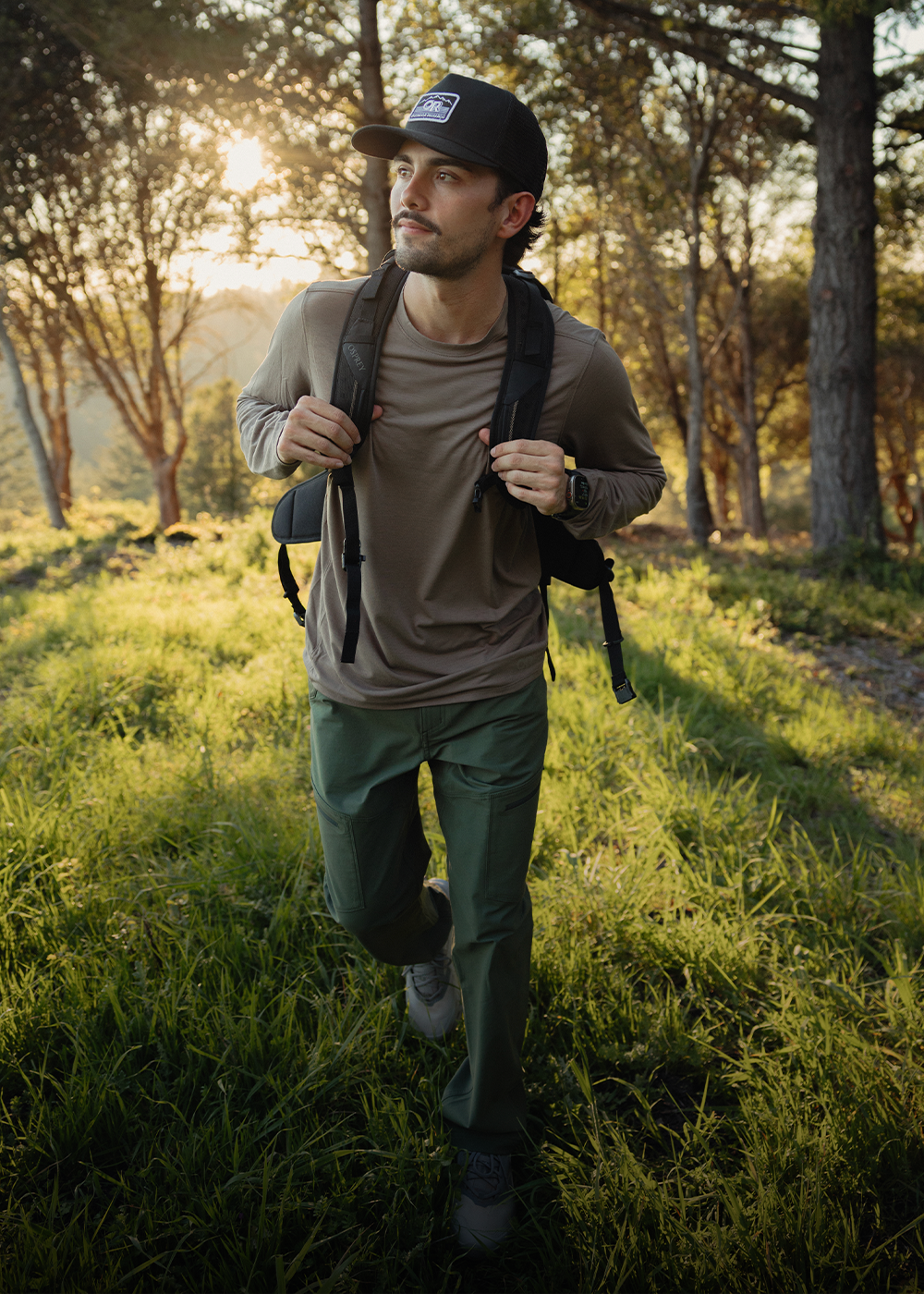 Male hiking up the rocks wearing Outdoor Research Men's Helium UL Jacket Atlantic and Swift Lite Tech Cap Skyline. 