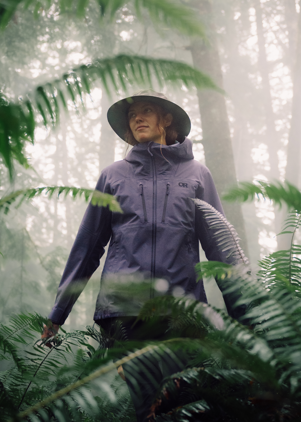 Two females in the rain wearing Outdoor Research Women's Helium UL Jackets Madrone Red and Oyster. 