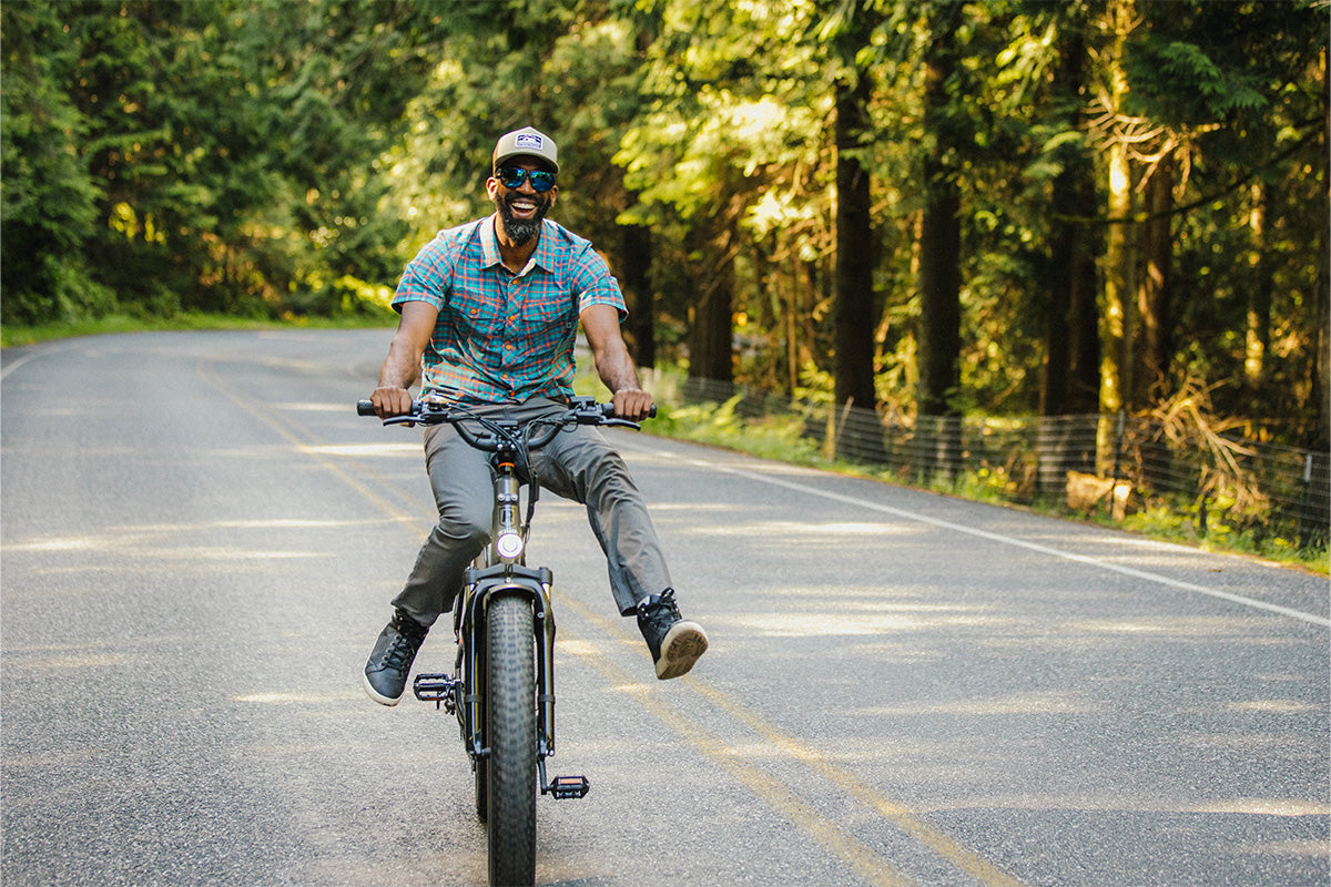 A man in a hat smiles while riding his bike.