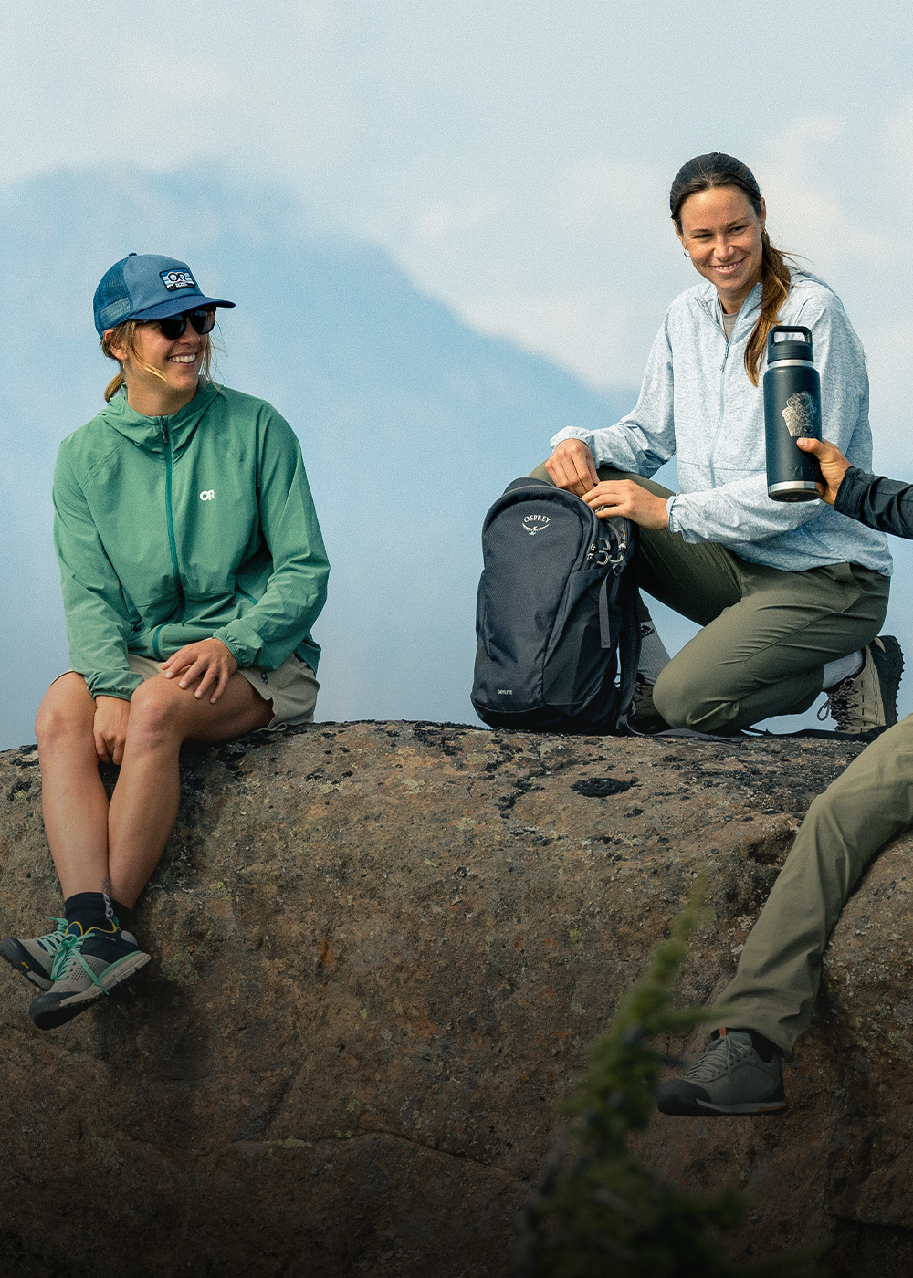 Four hikers resting at the top of the hill wearing Outdoor Research sportswear. 