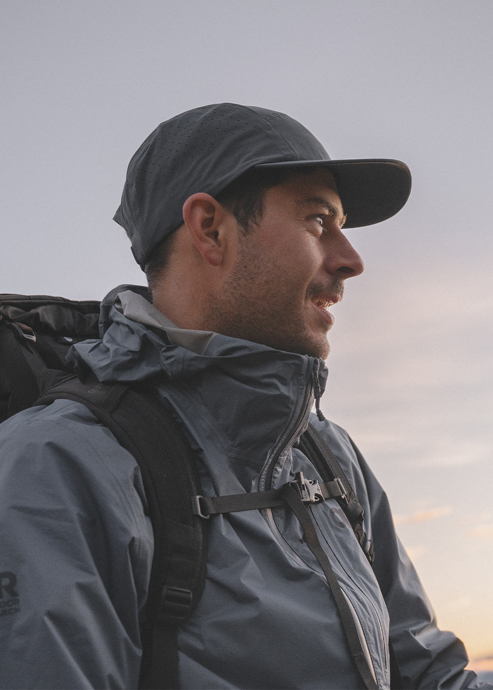 Mens Outdoor Research sportswear and outerwear lies on a dark green drop cloth with brown gift boxes, holly, and pine cones.