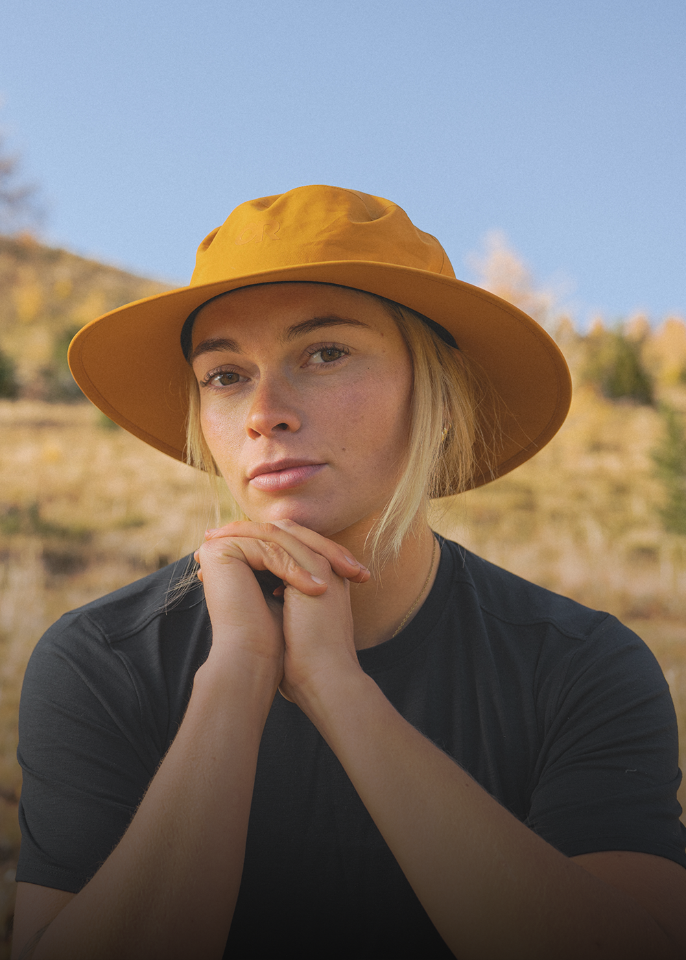 Female sitting in the sun wearing Outdoor Research Stratoburst Rain Hat Sedona. 