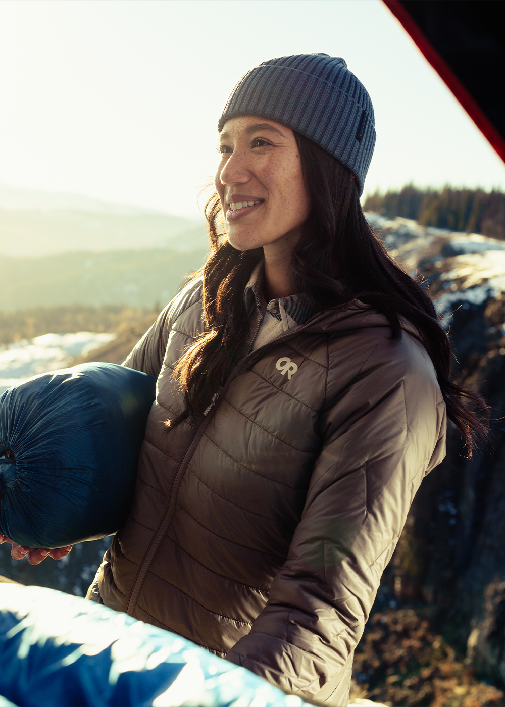 Two friends walk along the ledge of a rock cliff with a desert plateau behind them.